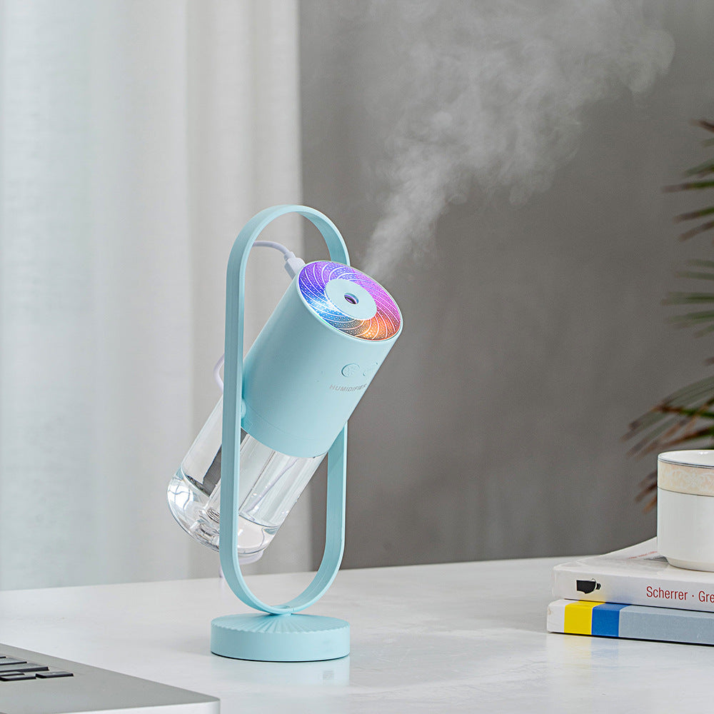 Aurora projection humidifier in navy on a round white side table, mist rising
