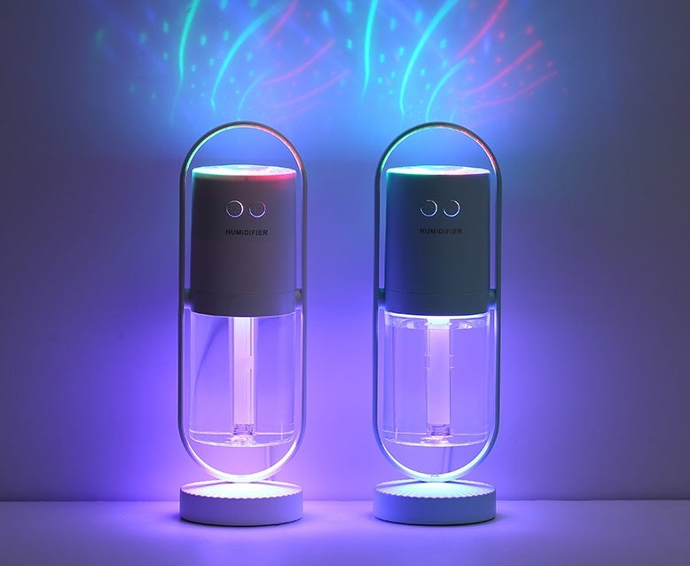 Two Aurora humidifiers projecting blue and green light in a dark room