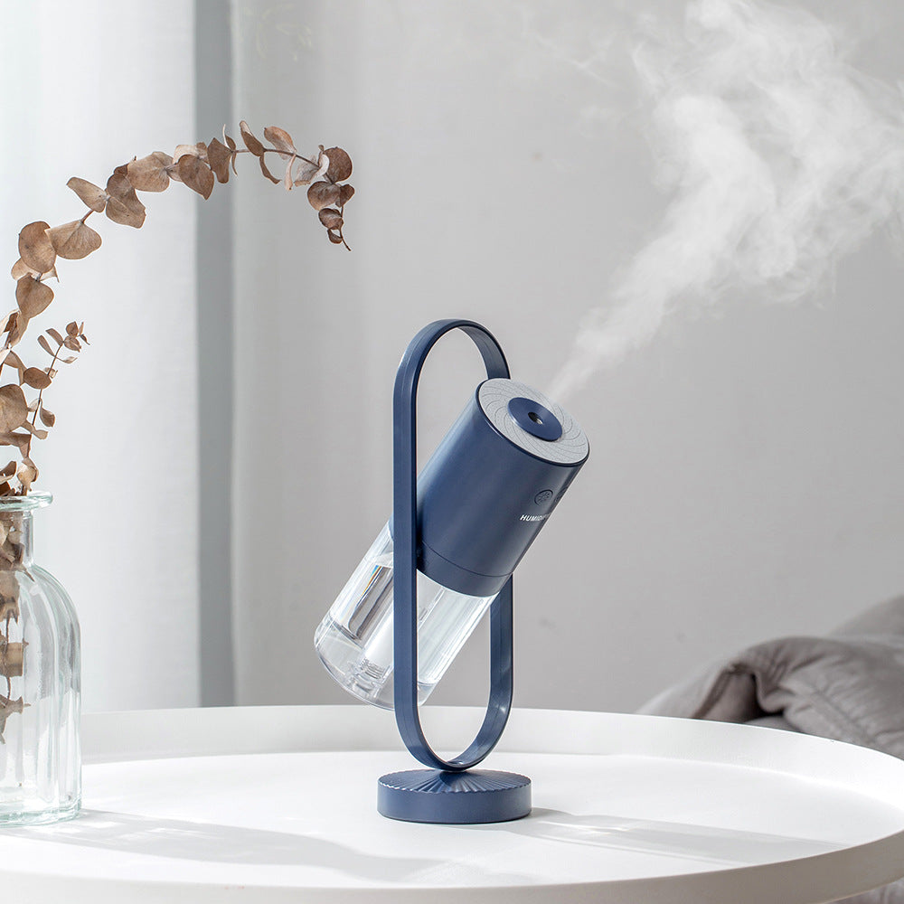 Aurora projection humidifier in pink on a wooden desk by a window
